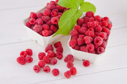 Fresh raspberries in cardboard boxes on a white wooden table