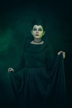 Maleficent demonic - starring. Beautiful woman from a fairytale with hair horns outdoor. Beautiful girl with horns dressed up as devil. Woman with makeup, nail polish. Fantasy. Halloween concept.