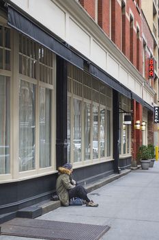 man sitting on the sidewalk beside a bar window