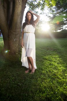 young woman wearing a white dress beside a tree