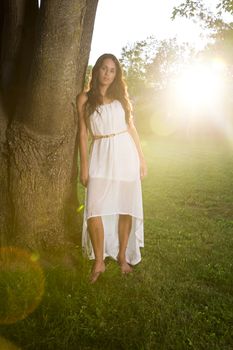 twenty something woman standing outside in the sun, wearing a white dress