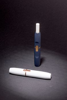 Newest electronic cigarettes, heating tobacco system IQOS, smoking, device isolated on black background