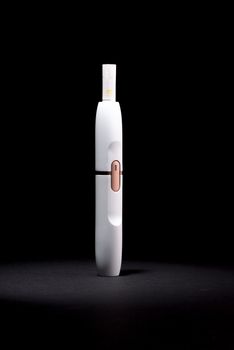 Newest electronic cigarettes, heating tobacco system IQOS, smoking, device isolated on black background