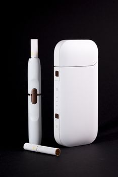 Newest electronic cigarettes, heating tobacco system IQOS, smoking, white isolated on black background