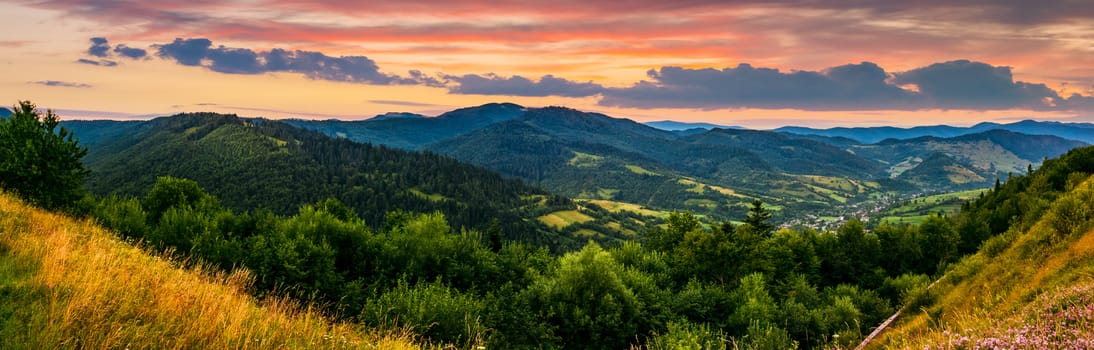 panorama of mountain ridge with peak behind the hillside. beautiful summer background at sunset with red sky