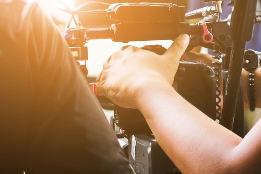 Cameraman with his video camera shooting, Hands Adjusting Camera,film production crew, behind the scenes background.