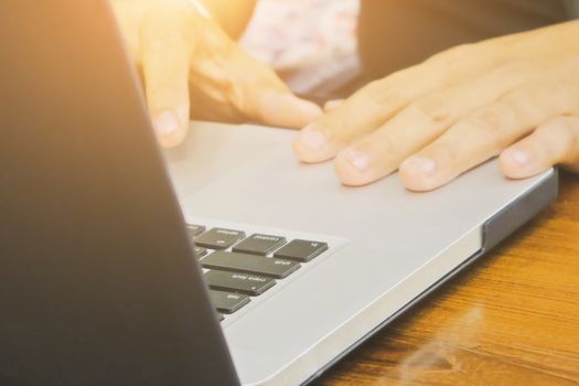 Close-up of female hands using laptop computer, working on laptop with flare light background. Searching Internet ,Social Networking Concept