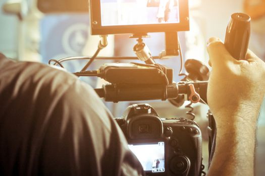 Cameraman with his video camera shooting, Hands Adjusting Camera,film production crew,behind the scenes background.