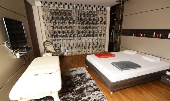 Large bedroom with king size bed massage table and plasma television