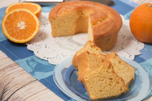 Homemade orange cake on a table with fruit sliced.