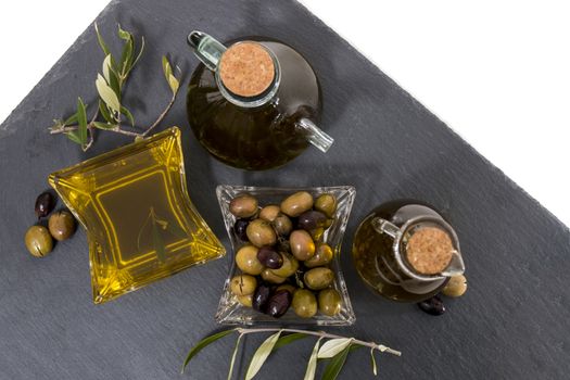 Green and black olives with olive oil bottles isolated on a white background.