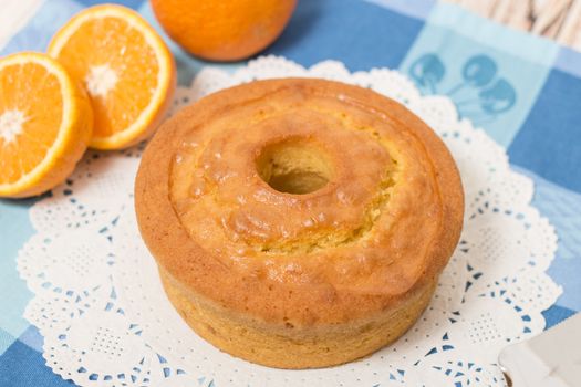 Homemade orange cake on a table with fruit sliced.