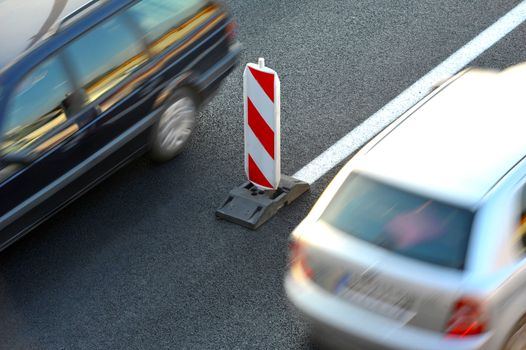 Road under construction with red and white sign