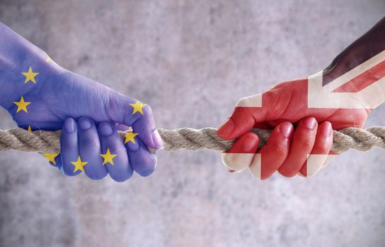 Tug of war between hands painted with UK and European flags 