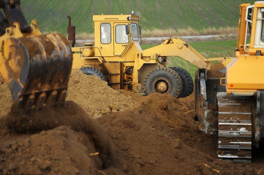 Big bulldozer and excavator in action on construction site