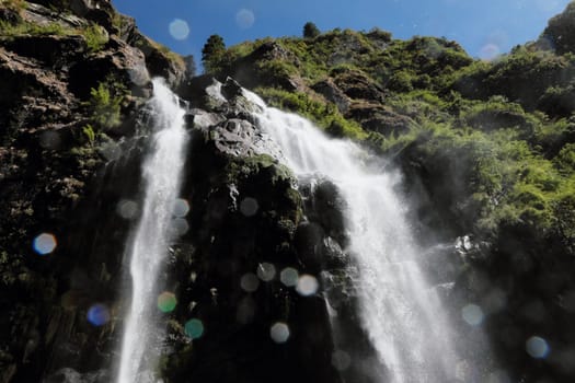 Waterfall in the mountains in Nepal with lense flares 