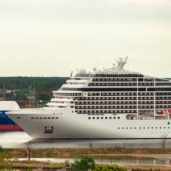 Big white cruise liner sailing past the cargo port