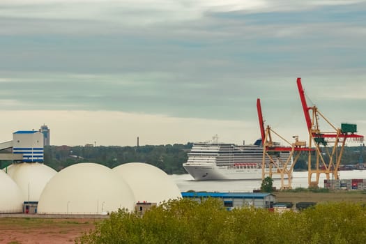 Big white cruise liner sailing past the cargo port