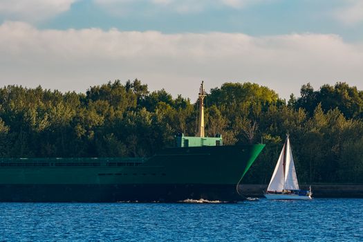 Green cargo ship leaves the port in a clear day