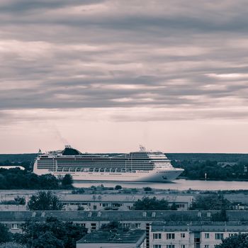 Large cruise liner sailing past the cargo port. Monochrome