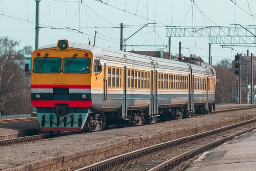 Old yellow passenger diesel train moving at the terminal