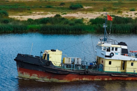 Old tug ship moving to the cargo terminal. Industrial service