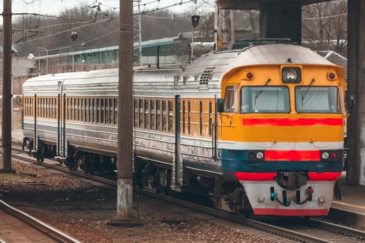 Old yellow passenger diesel train moving at the terminal