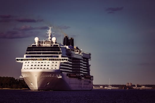 Giant white passenger ship moving past the port on a clear day