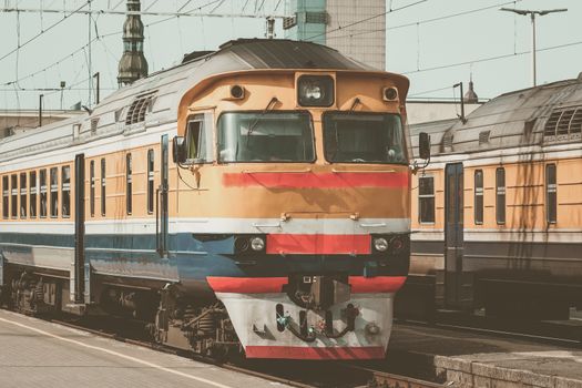 Old yellow passenger diesel train moving at the terminal