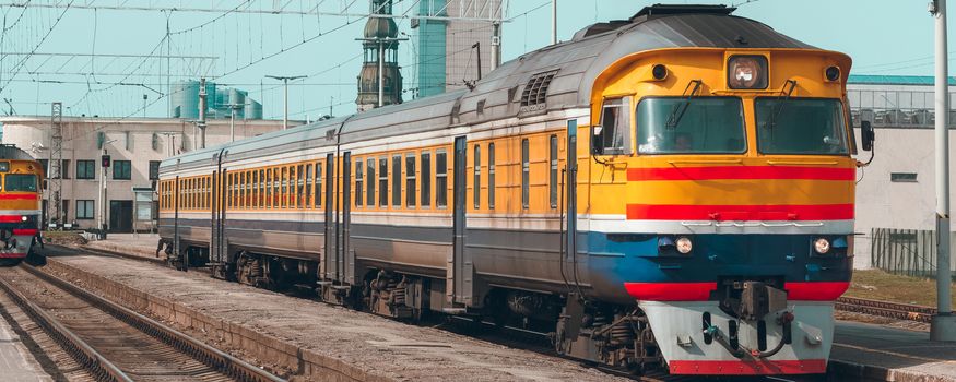 Old yellow passenger diesel train moving at the terminal