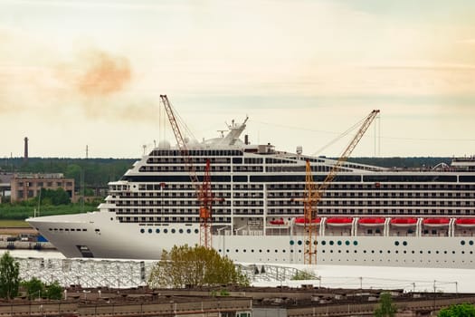 Big white cruise liner sailing past the cargo port