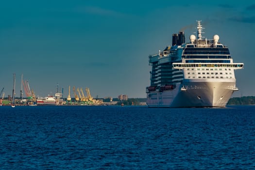 Giant white passenger ship moving past the port on a clear day