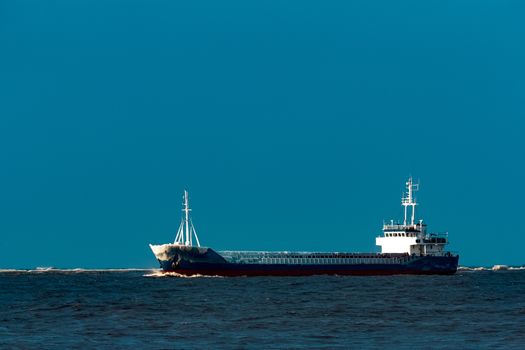 Blue bulk carrier moving from the sea in cold winter