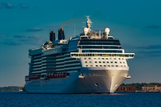 Giant white passenger ship moving past the port on a clear day