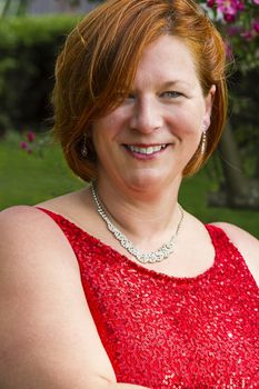 woman in her forties wearing a red dress and jewelry