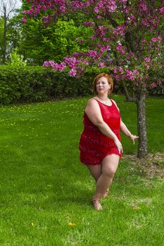 woman wearing a red dress dancing under a cherry tree in bloom