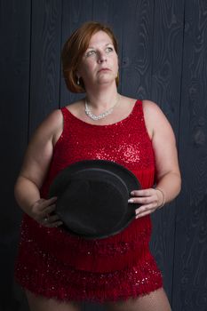 forty year old woman wearing a sparkly dress and holding a black hat