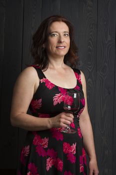 forty year old woman wearing a summer dress, holding a glass of red wine