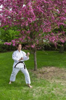woman in martial art stance under a cherry tree in bloom