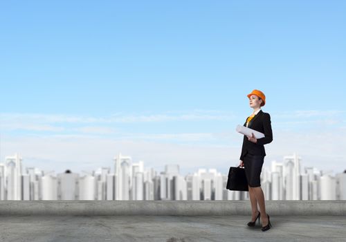 Young woman architect in hardhat holding project in hand