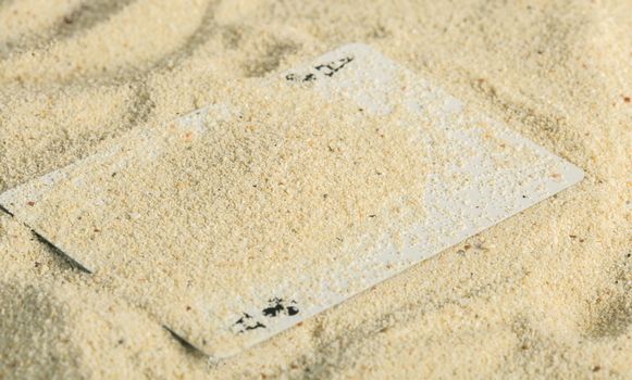 Poker playing cards buried  in a sand dune