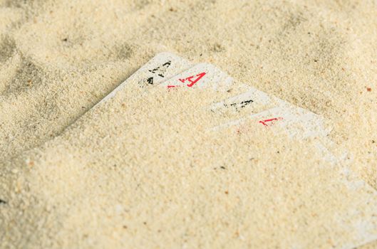 Poker playing cards buried  in a sand dune