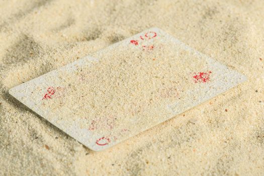 Poker playing cards buried  in a sand dune