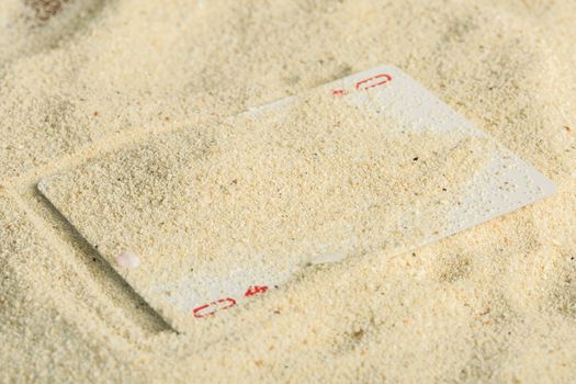 Poker playing cards buried  in a sand dune