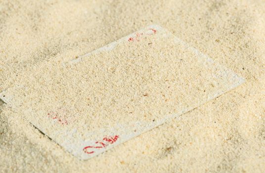 Poker playing cards buried  in a sand dune