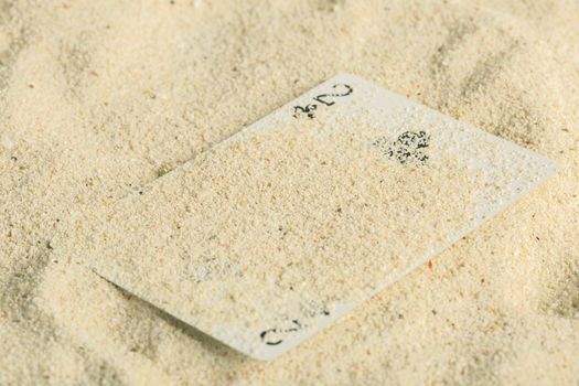 Poker playing cards buried  in a sand dune