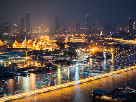 High view of Chaopraya river and light of transportation by boat with Grand Palace and background of high building in Bangkok,Thailand