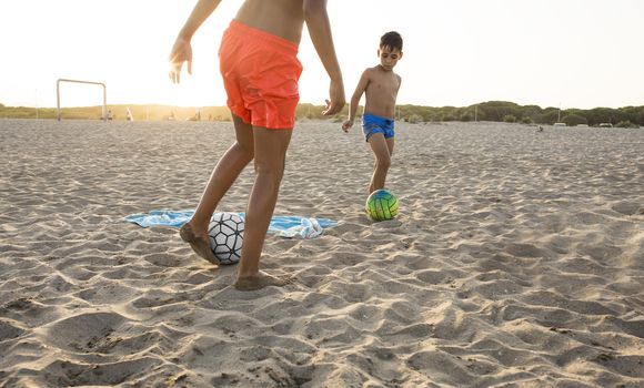 Boy playing football  on the beach