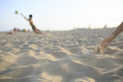 Boy playing football  on the beach