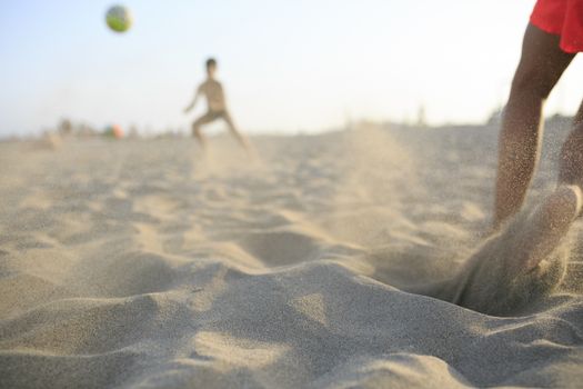 Boy playing football  on the beach